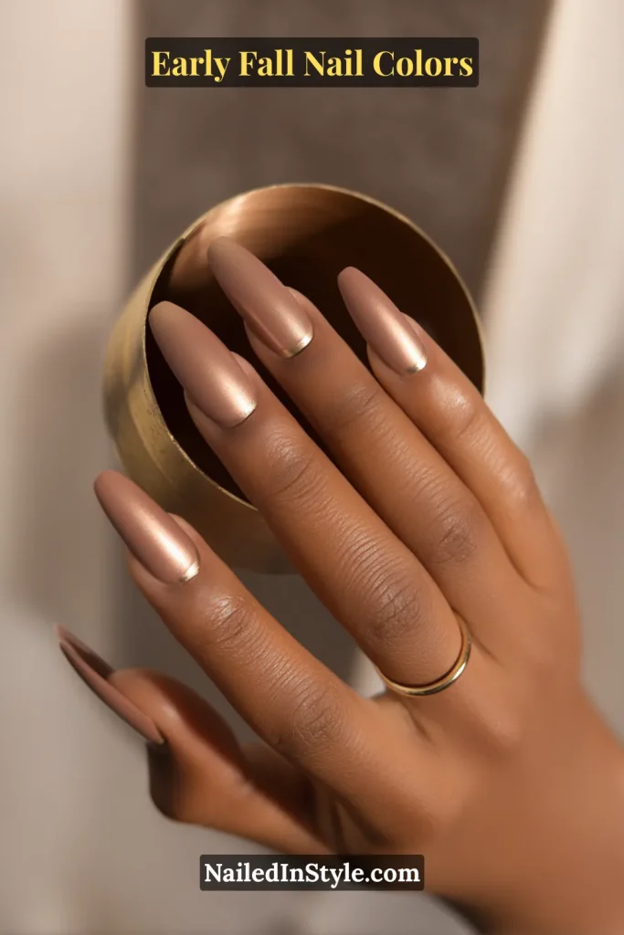 Early fall nail colors in taupe with a whisper-thin bronze crescent arc at the cuticle, styled with gold jewelry.