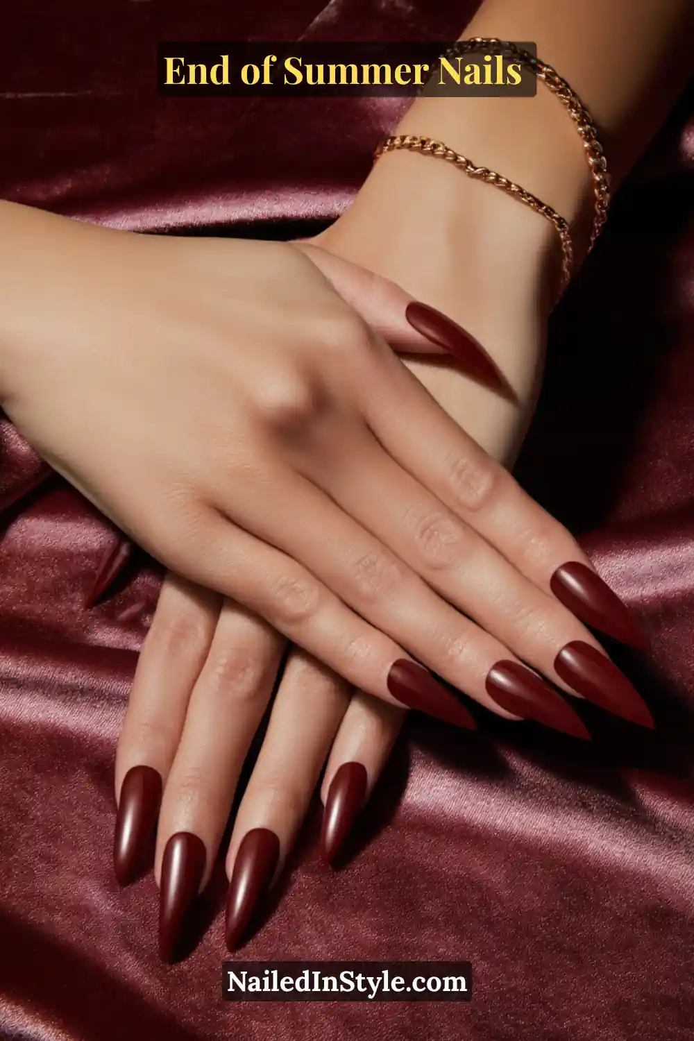 Close-up of long stiletto nails painted in deep burgundy red polish for a bold, glamorous look.