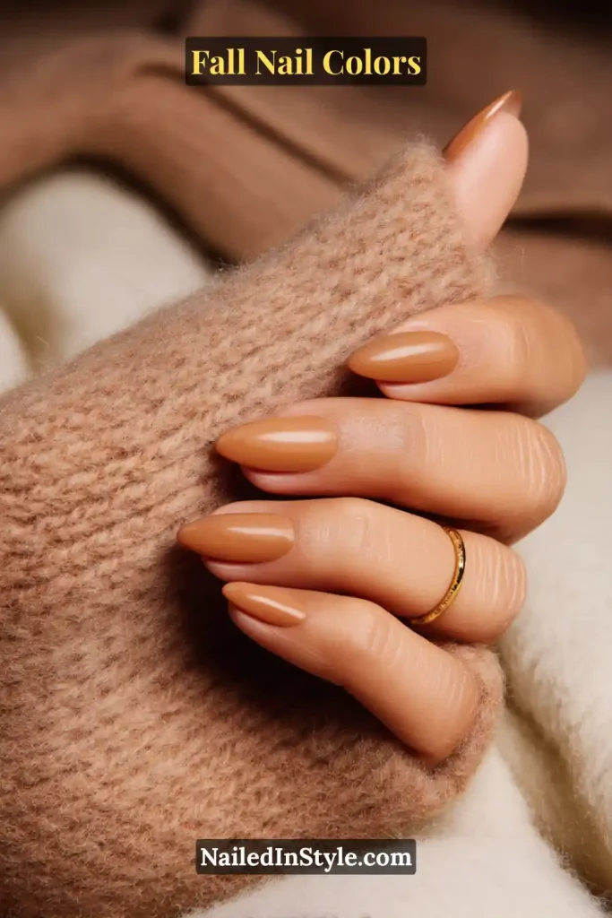 Close-up of caramel nude almond-shaped nails with a soft glossy finish, styled with a cozy knit sweater.