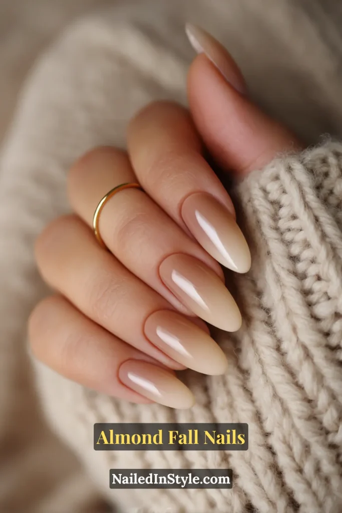 Almond-shaped nails with a nude base blending seamlessly into warm caramel tips, styled with a beige knit scarf.
