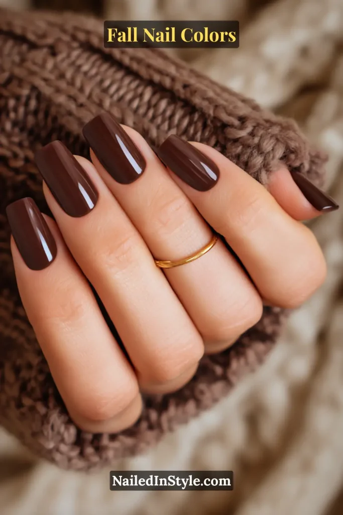 Close-up of short square nails painted in deep chocolate brown on tan skin, styled against a chunky knit sweater.