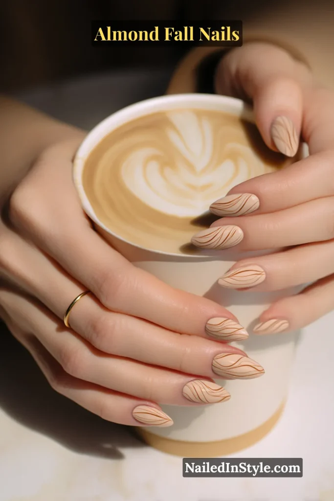 Almond nails with latte beige base and mocha swirl line art, styled holding a latte cup with foam art.