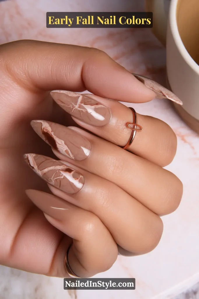 Early fall nail colors in latte nude with thin mocha marble swirls, styled beside a marble board and coffee mug.