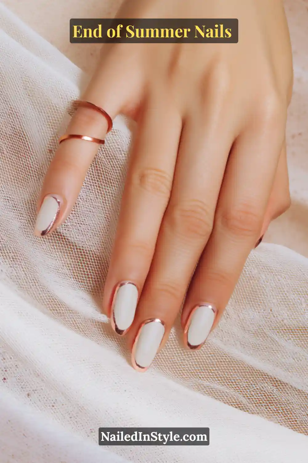 Hand with almond-shaped nails featuring a nude base and shiny copper foil accents around the edges.