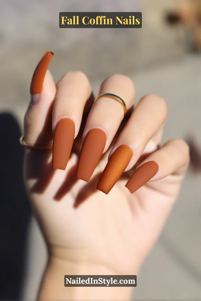 fall coffin nails in copper split finish, half matte and half glossy, catching the light with a bold coffin tip design