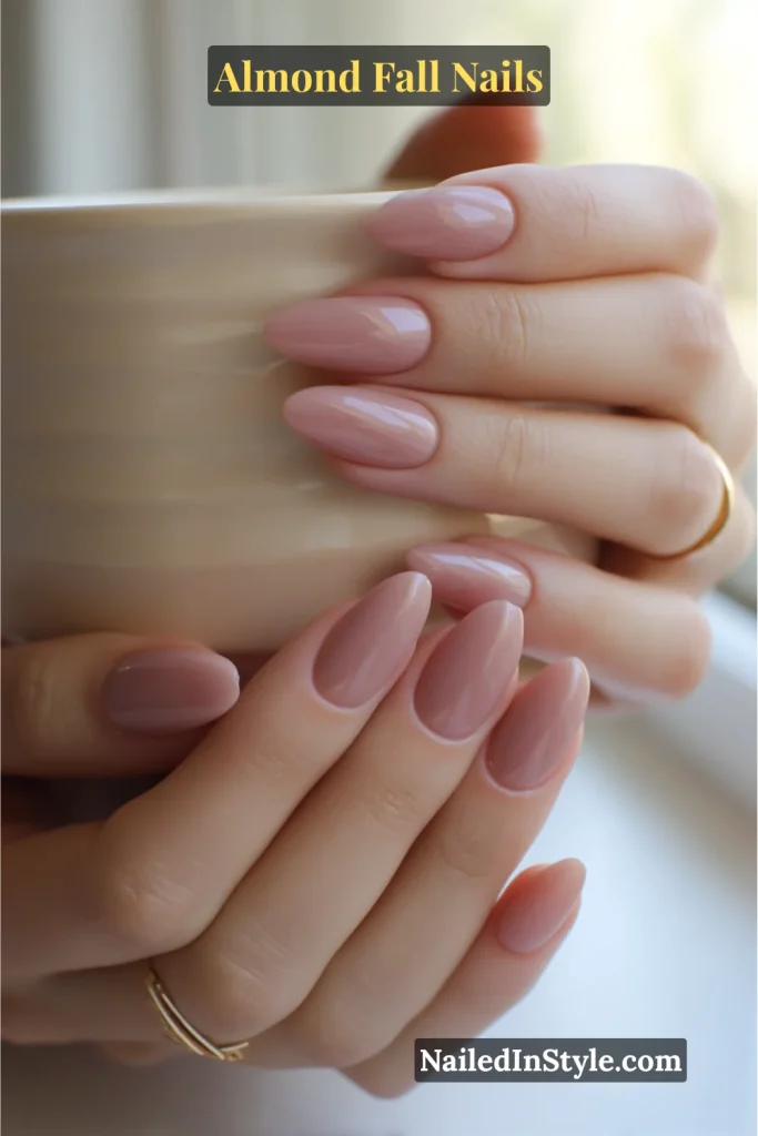 Almond nails in dusty rose pink with soft milky gloss, holding ceramic mug.