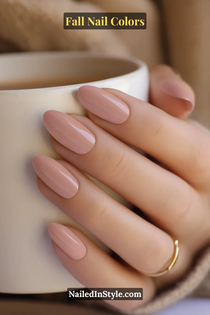 Close-up of soft dusty rose almond-shaped nails on fair skin holding a warm coffee cup.