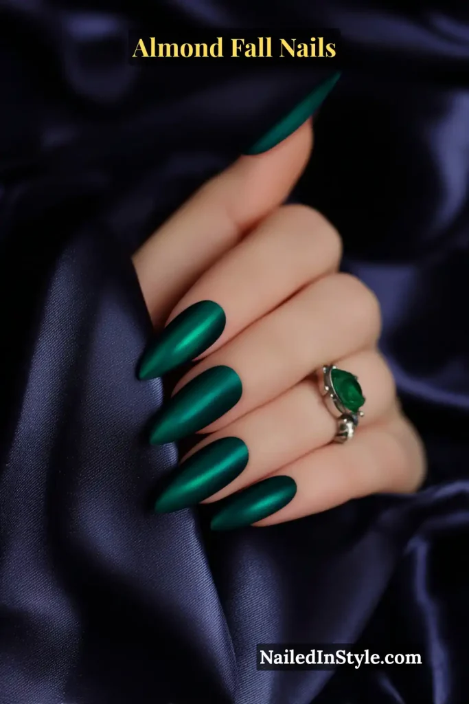 Almond nails in emerald green cat-eye finish with magnetic stripe effect, styled with satin sleeve and silver ring.