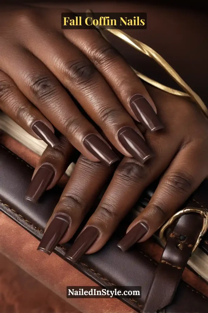 fall coffin nails in espresso brown with a negative-space band across the mid-plate, styled holding a leather strap