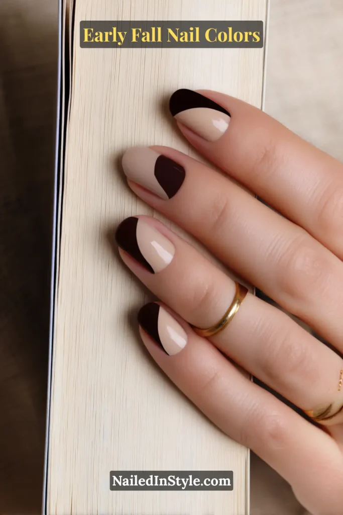 Early fall nail colors in a nude base with asymmetrical espresso arcs, styled against a book spine for a cozy autumn vibe.