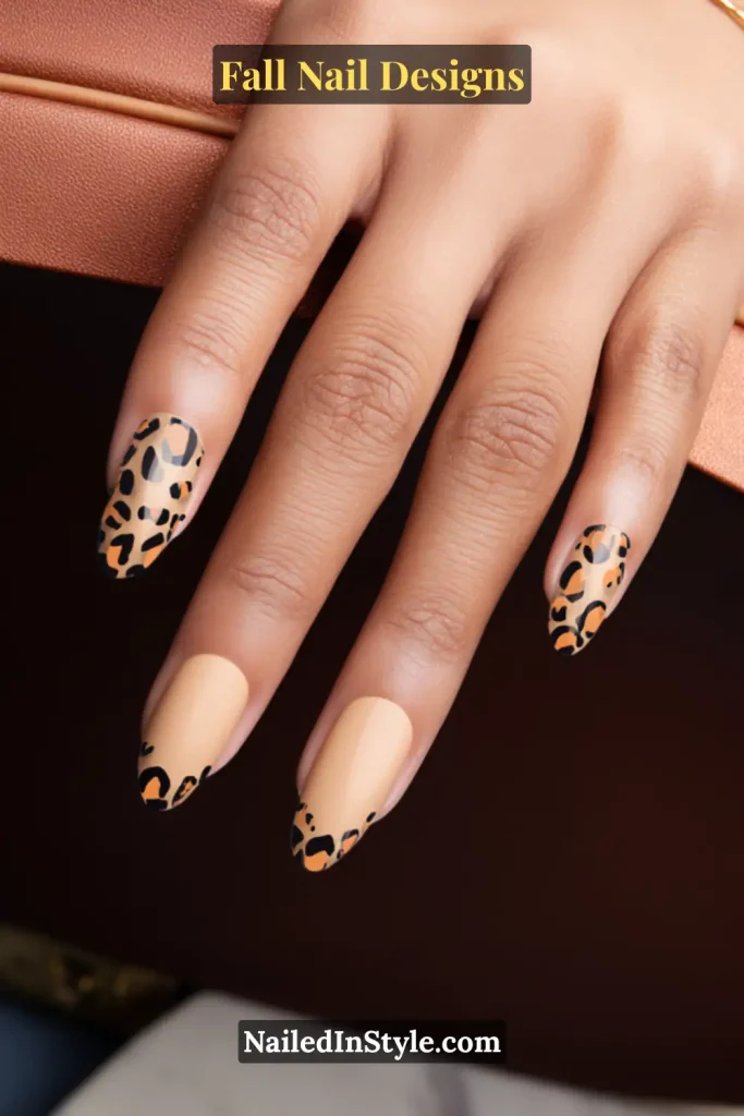Almond nails in nude with glossy leopard print French tips, hand near leather strap.
