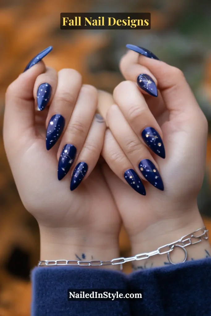 Almond nails in glossy navy with white star dot art, hands in velvet blazer sleeve.