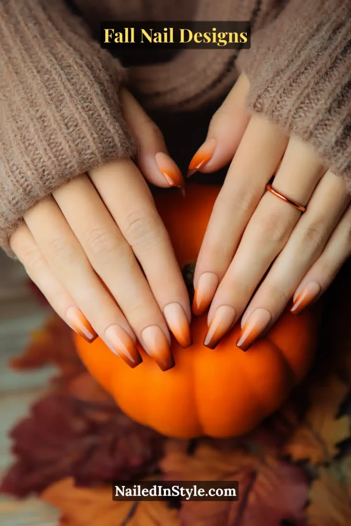 Coffin nails with orange ombré gradient from nude base to tips, hands holding a pumpkin.