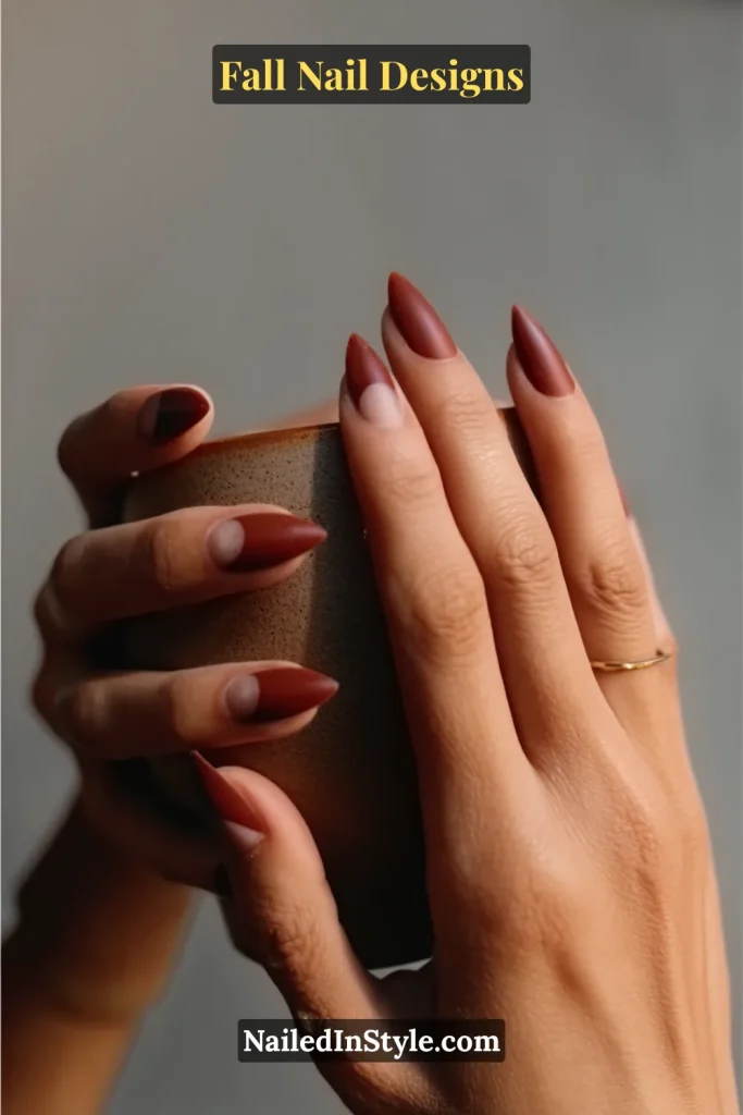 Almond nails in matte terracotta with negative-space half moons, hands holding a clay mug.
