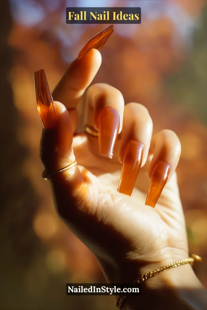 Fall Nail Ideas: 21 Gorgeous Looks to Try Now 9 Coffin nails in translucent amber jelly, hand raised to sunlight.
