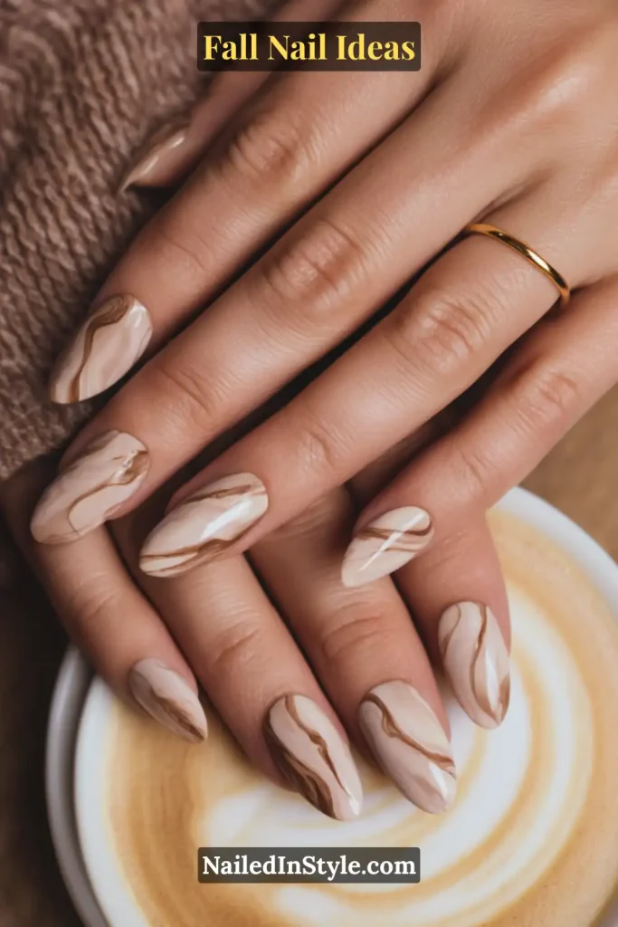 Fall Nail Ideas: 21 Gorgeous Looks to Try Now 10 Almond nails in beige with mocha marble swirl art, hand over latte.