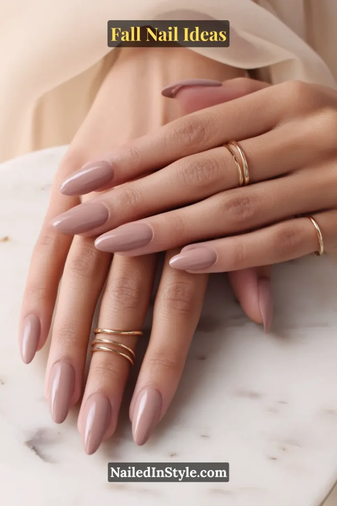 Fall Nail Ideas: 21 Gorgeous Looks to Try Now 4 Almond nails painted in glossy mauve-taupe, hands with delicate gold rings on a marble table.