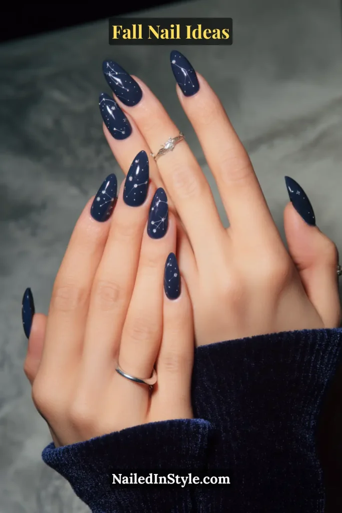 Fall Nail Ideas: 21 Gorgeous Looks to Try Now 18 Glossy navy almond nails with delicate white star and constellation dot art, styled with a navy velvet sleeve.