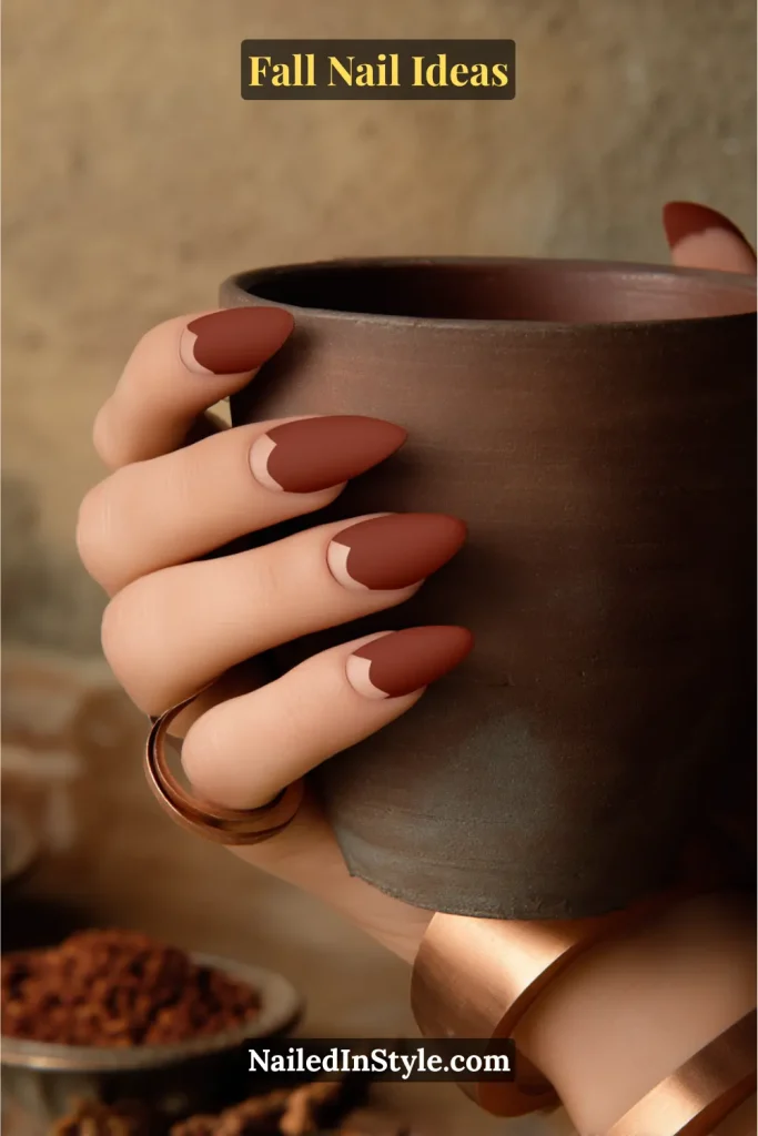 Fall Nail Ideas: 21 Gorgeous Looks to Try Now 17 Almond nails painted in rich matte terracotta with clean negative-space half-moons at the cuticle, styled holding a rustic clay mug.