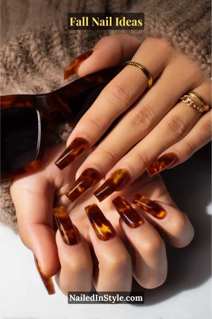 Fall Nail Ideas: 21 Gorgeous Looks to Try Now 6 Long coffin nails in glossy amber-brown tortoiseshell design, paired with tortoise sunglasses.