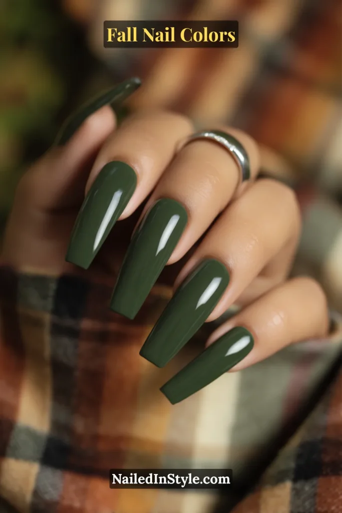 Close-up of long coffin-shaped forest green nails on medium skin styled with plaid flannel clothing.