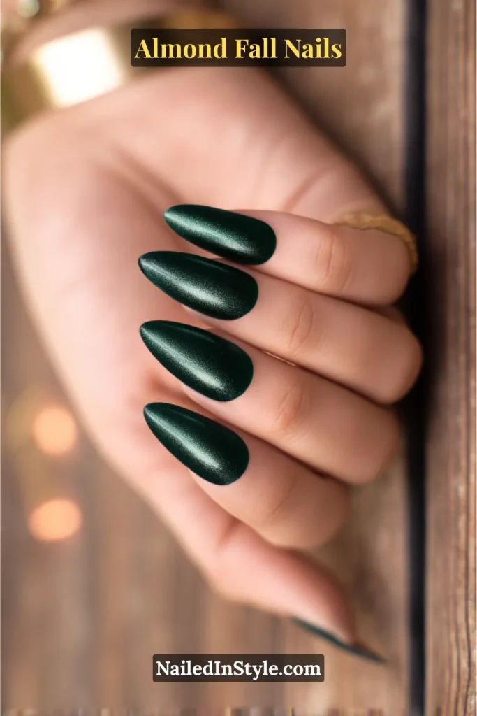 Almond-shaped nails in deep forest green velvet polish with a magnetic cat-eye sheen, shown with candle bokeh on wood background.