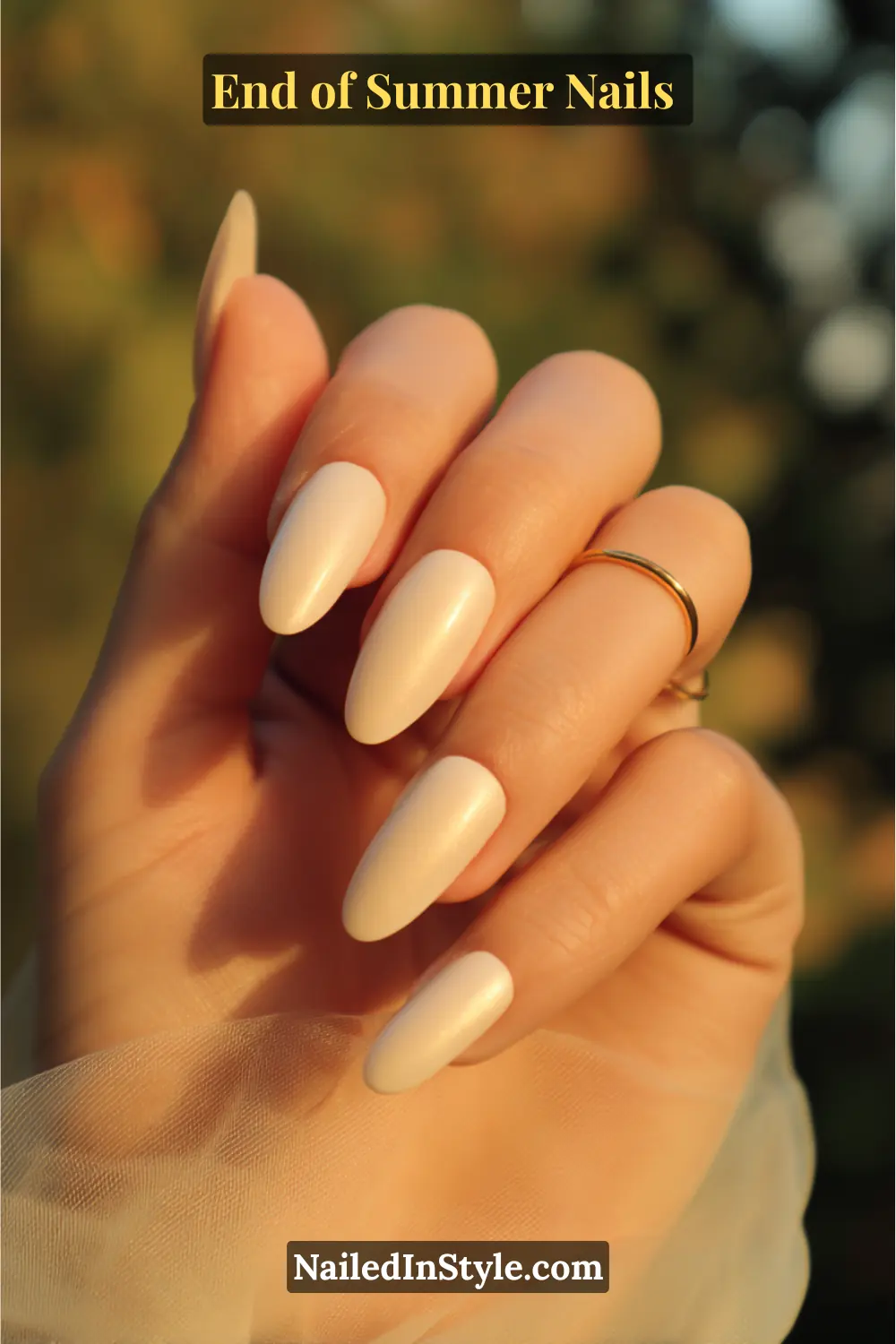 Close-up of almond-shaped nails with a nude base and golden chrome overlay glowing in the sunset light.