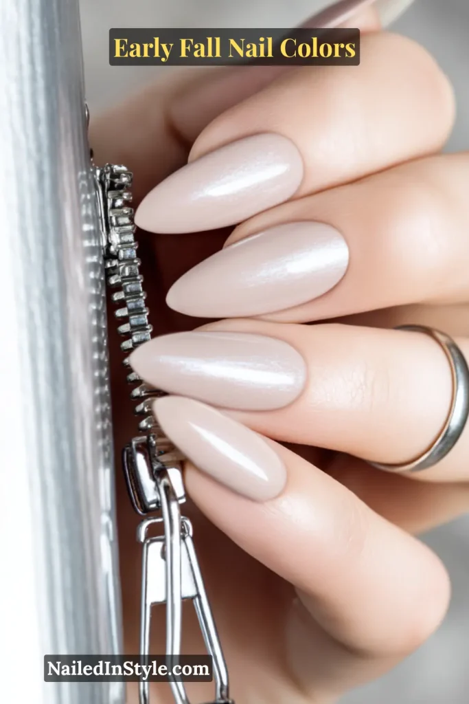 Early fall nail colors in soft nude with a pewter shimmer accent, styled with a metallic zipper pull macro shot.