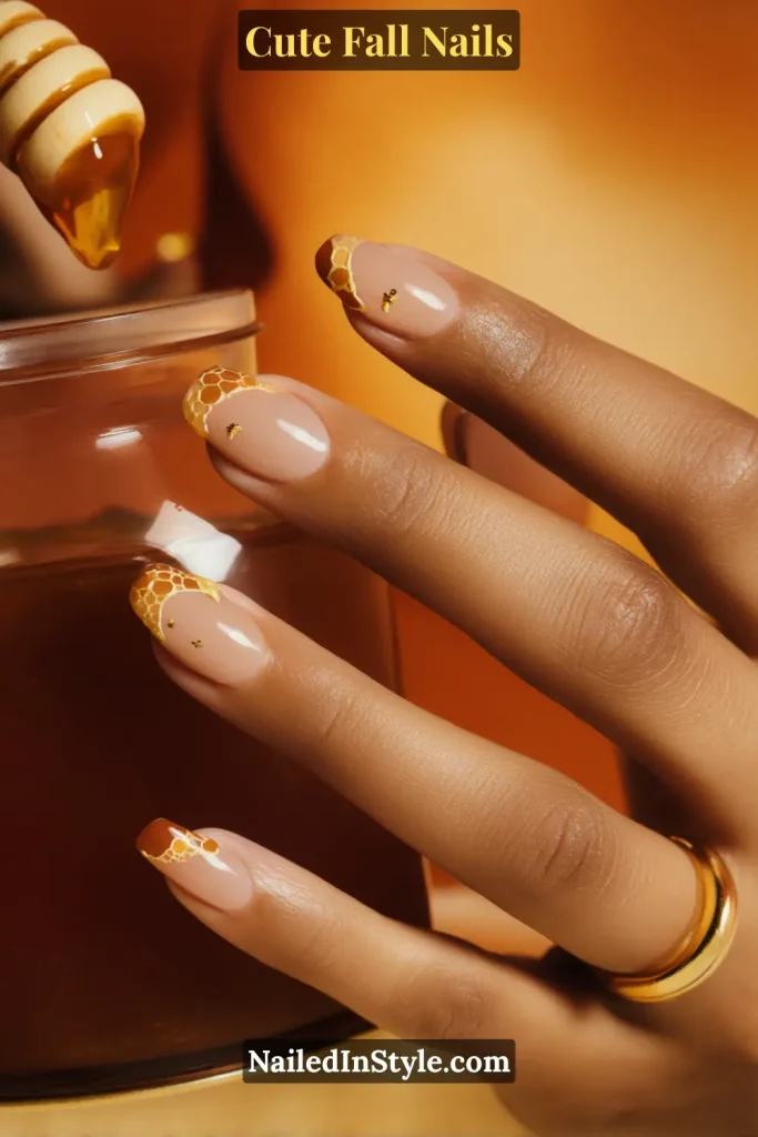 Tan and deep skin tone fall nails featuring golden honeycomb half-moons at the cuticle with tiny bee dot accents, styled with honey dipper and jar.