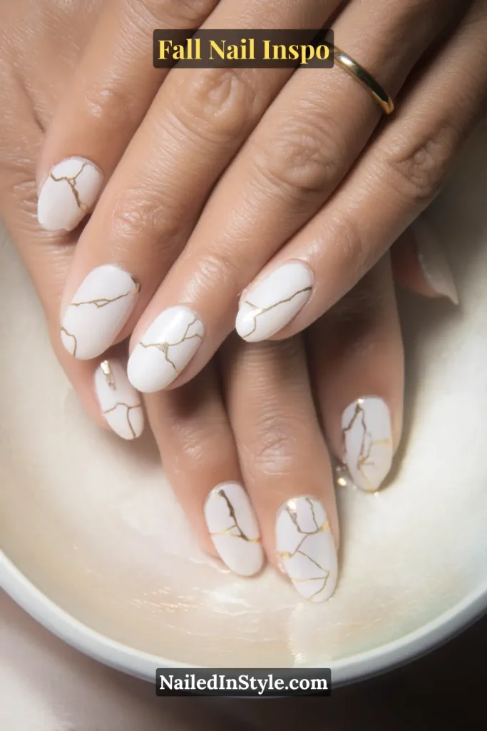 White glossy nails with fine gold lines resembling repaired cracks.