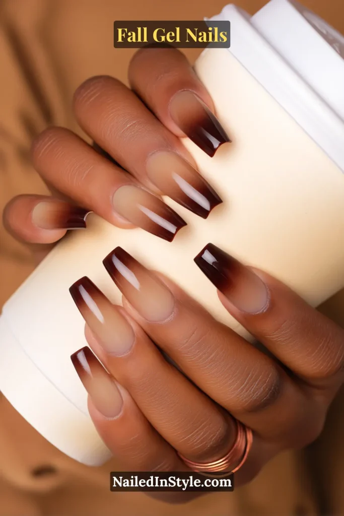 fall gel nails in mocha ombre fading from latte nude to deep espresso, coffin shape while holding a takeaway coffee cup