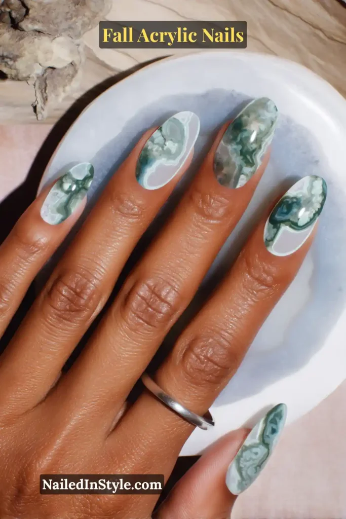 Oval acrylic nails with moss-agate inspired stone inlay design, swirls of green and white.