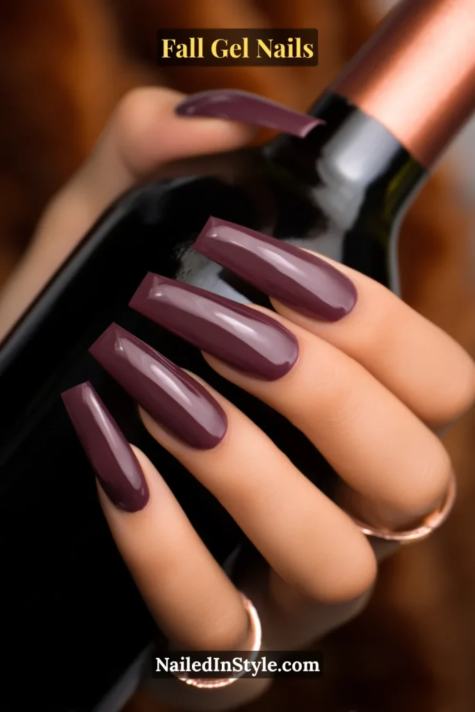 fall gel nails with plum French tips, glossy finish, long coffin shape, hand holding a wine bottle