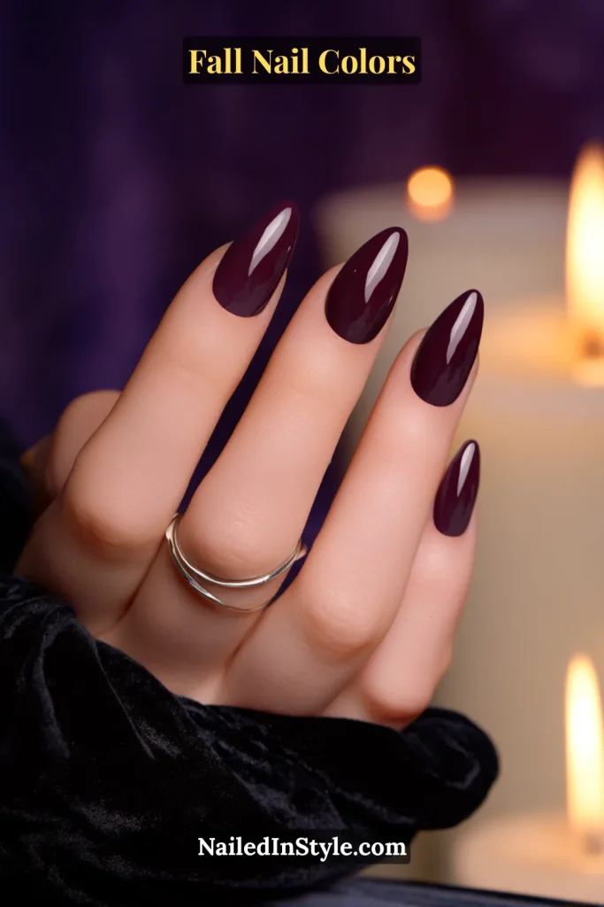 Close-up of glossy plum purple almond-shaped nails styled with silver rings, perfect for evening glam.