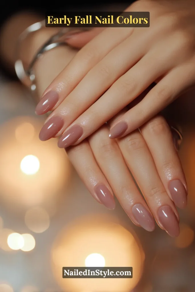 Early fall nail colors in sheer plum smoke veil style with soft candlelight bokeh in the background.