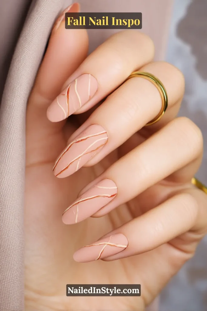 Taupe matte nails with fine saffron-colored line art strokes.