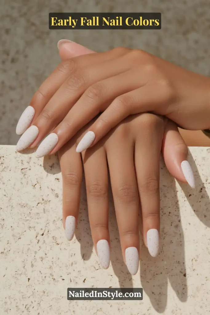 Early fall nail colors in greige with micro flecks, styled on a terrazzo concrete step for a natural stone effect.