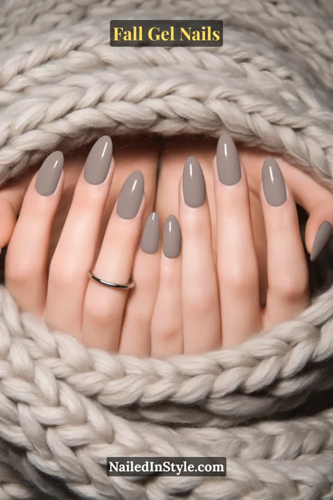 fall gel nails in smoky grey glossy finish, almond shape, hands wrapped in chunky knit blanket