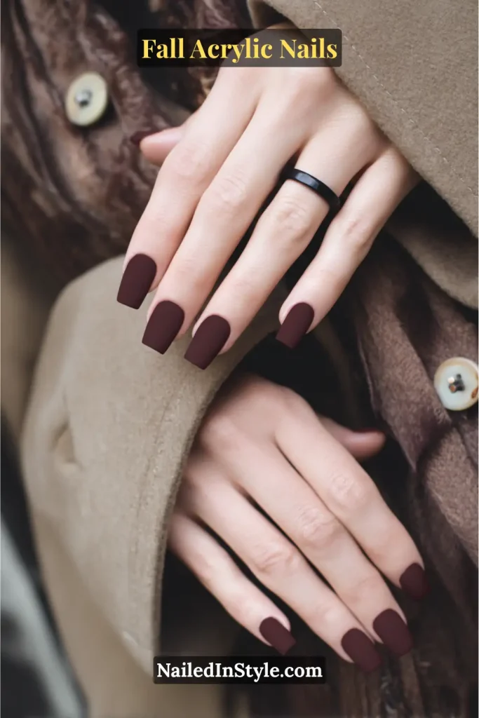 Short square acrylic nails in oxblood red with a matte, velvety finish, styled with a wool coat.