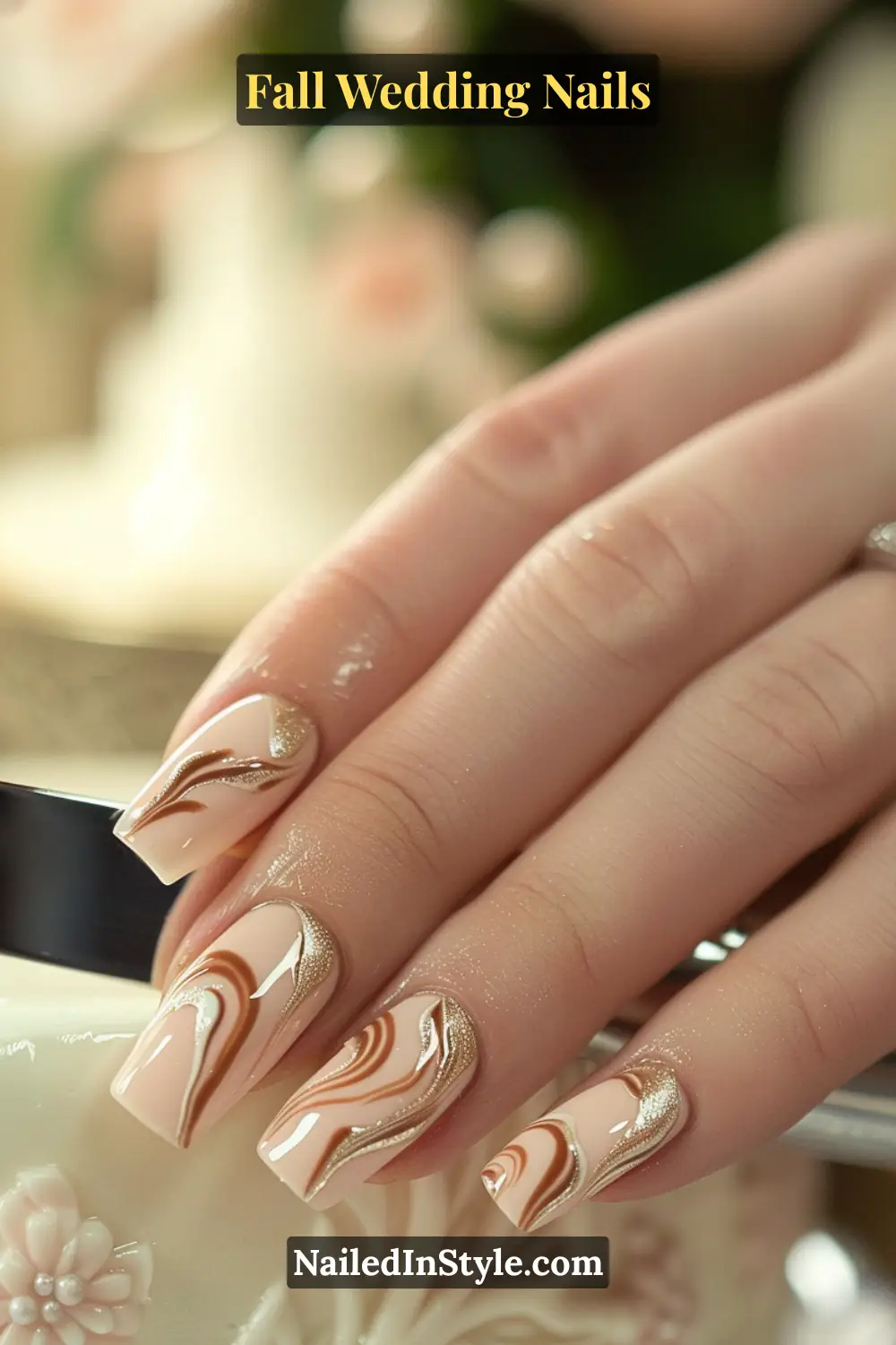 Close-up of fall wedding nails with ivory base and caramel swirl accents, bride’s hand cutting wedding cake.