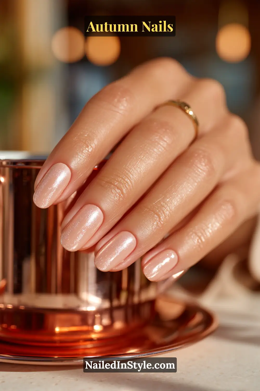 Close-up of copper glazed donut autumn nails with beige base and copper chrome top, styled against a copper candle holder.