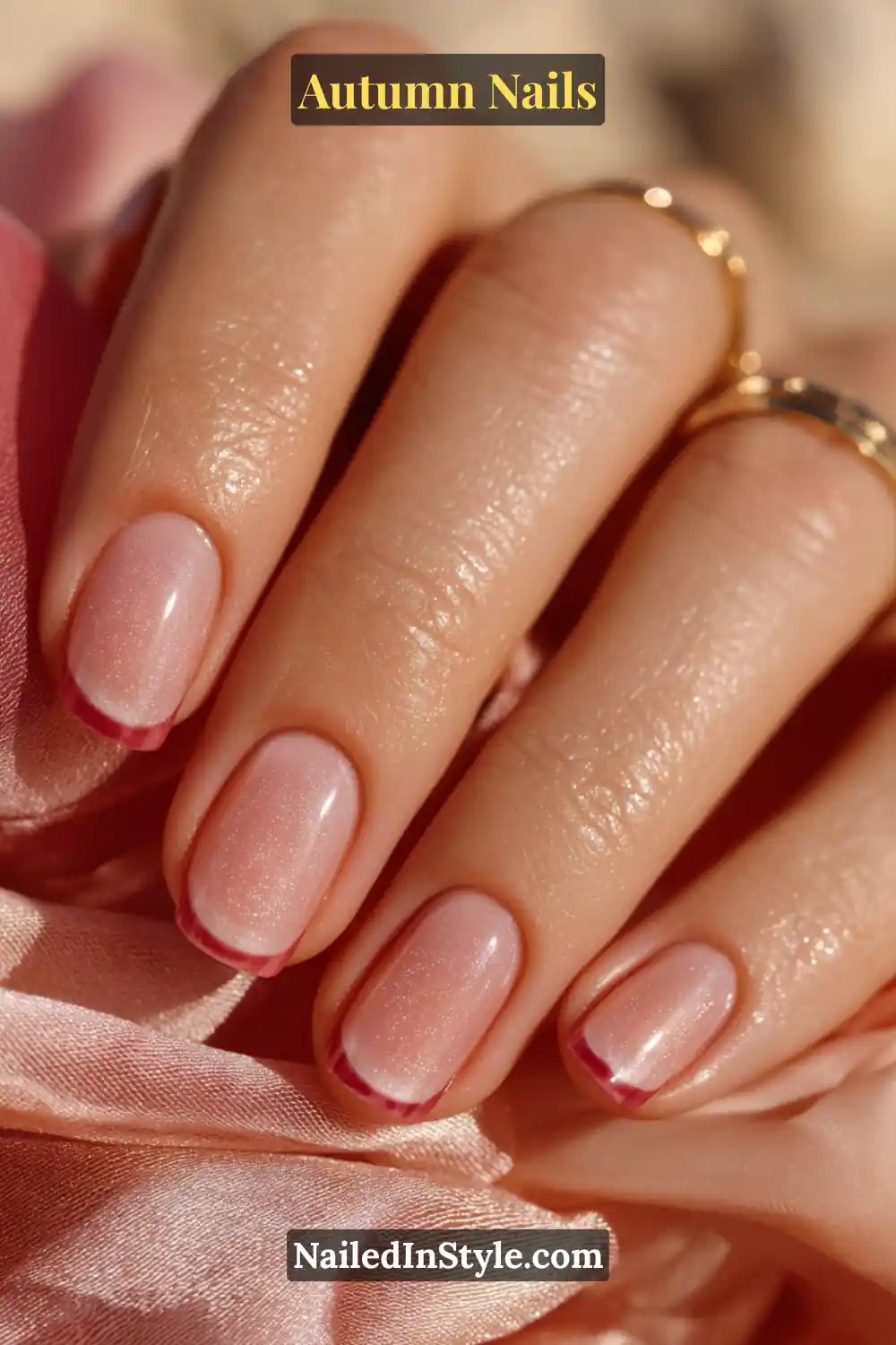 Close-up of cranberry blur French autumn nails with soft nude base and diffused cranberry French tips, holding a silk scarf.