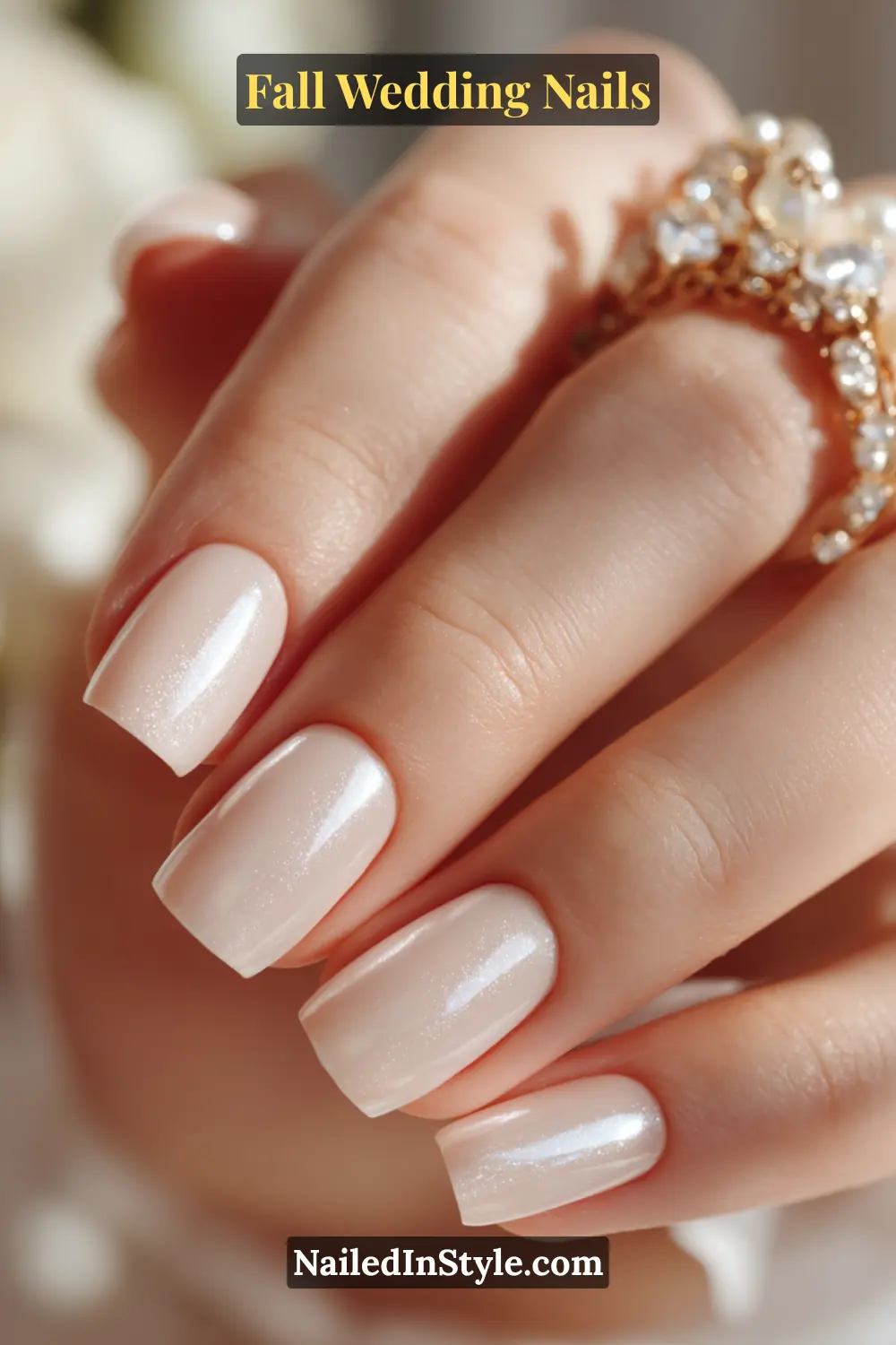 Close-up of fall wedding nails in sheer ivory with a pearly chrome glaze, styled with pearl-inspired rings.