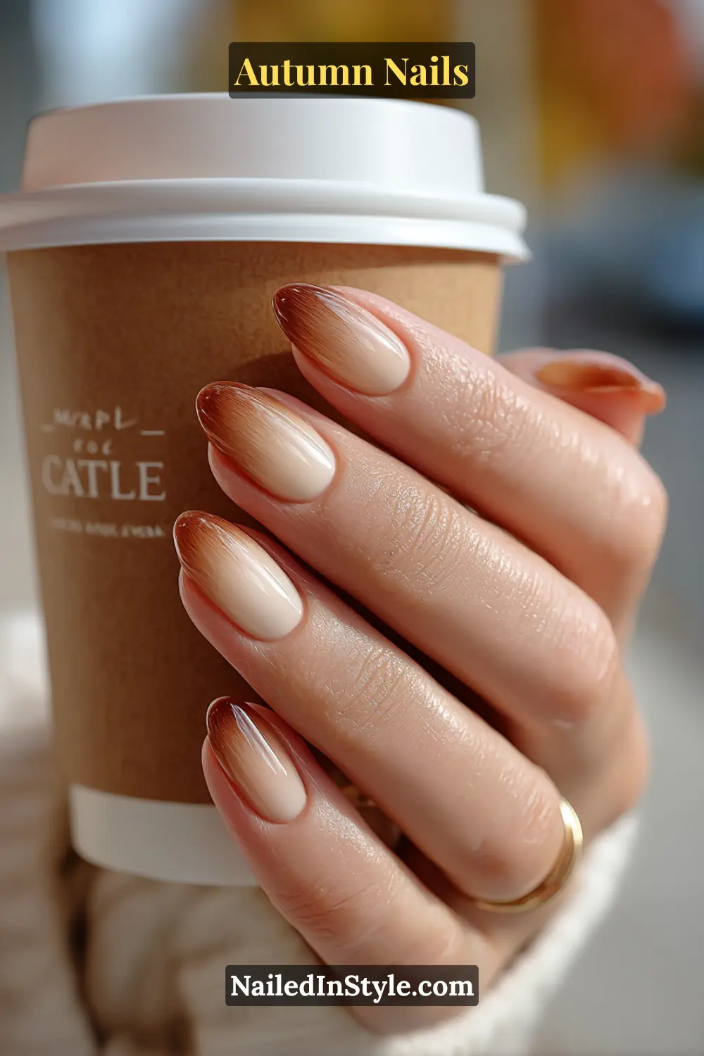 Close-up of maple latte gradient autumn nails with ombre fade from beige to maple brown, holding a takeaway coffee cup.