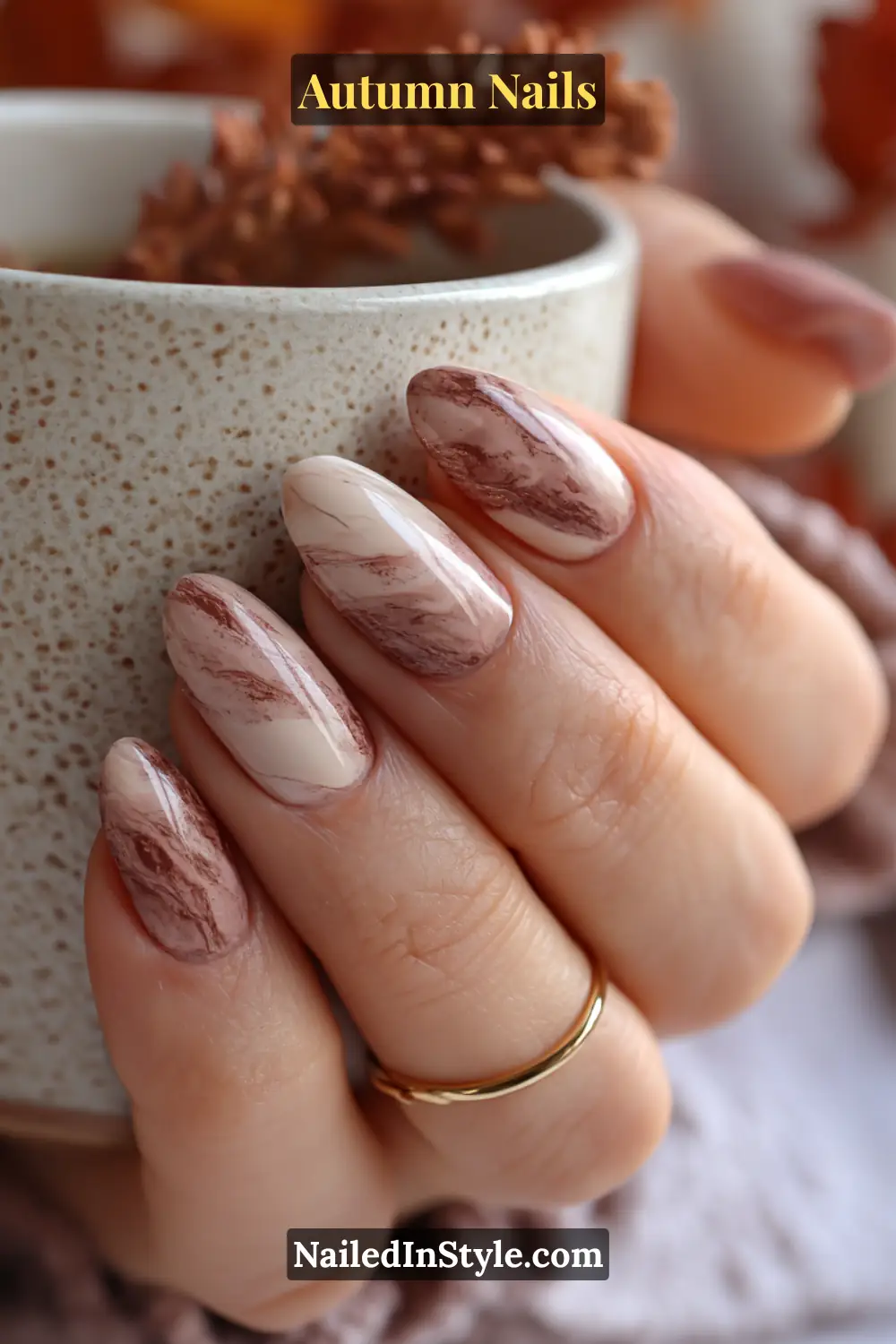 Close-up of mocha marble veins autumn nails with swirls of beige, mocha, and espresso tones, holding a ceramic mug.