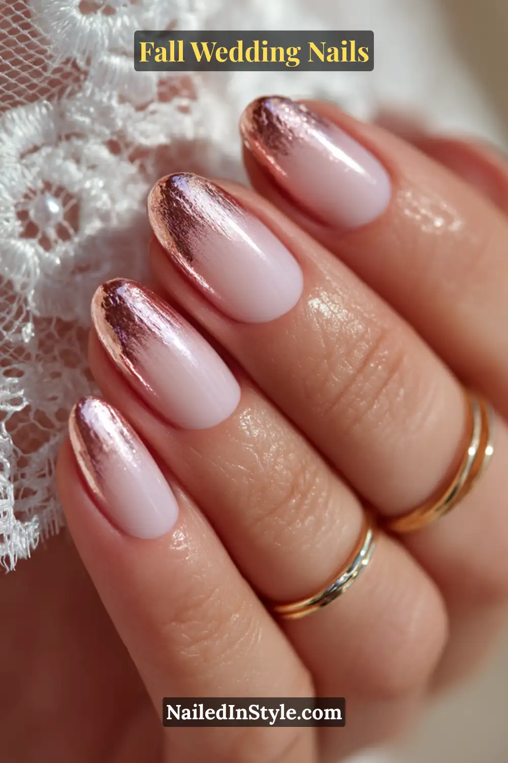 Close-up of fall wedding nails with a soft blush base fading into metallic rose gold tips, styled with gold rings and lace veil.