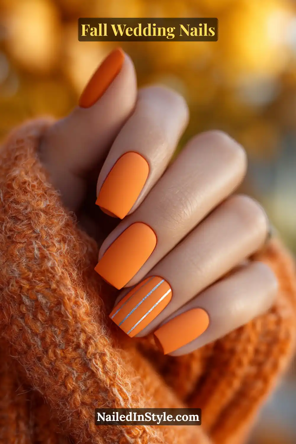 Bride’s hand with saffron orange matte nails featuring subtle glossy stripe accents, wrapped in an autumn shawl.