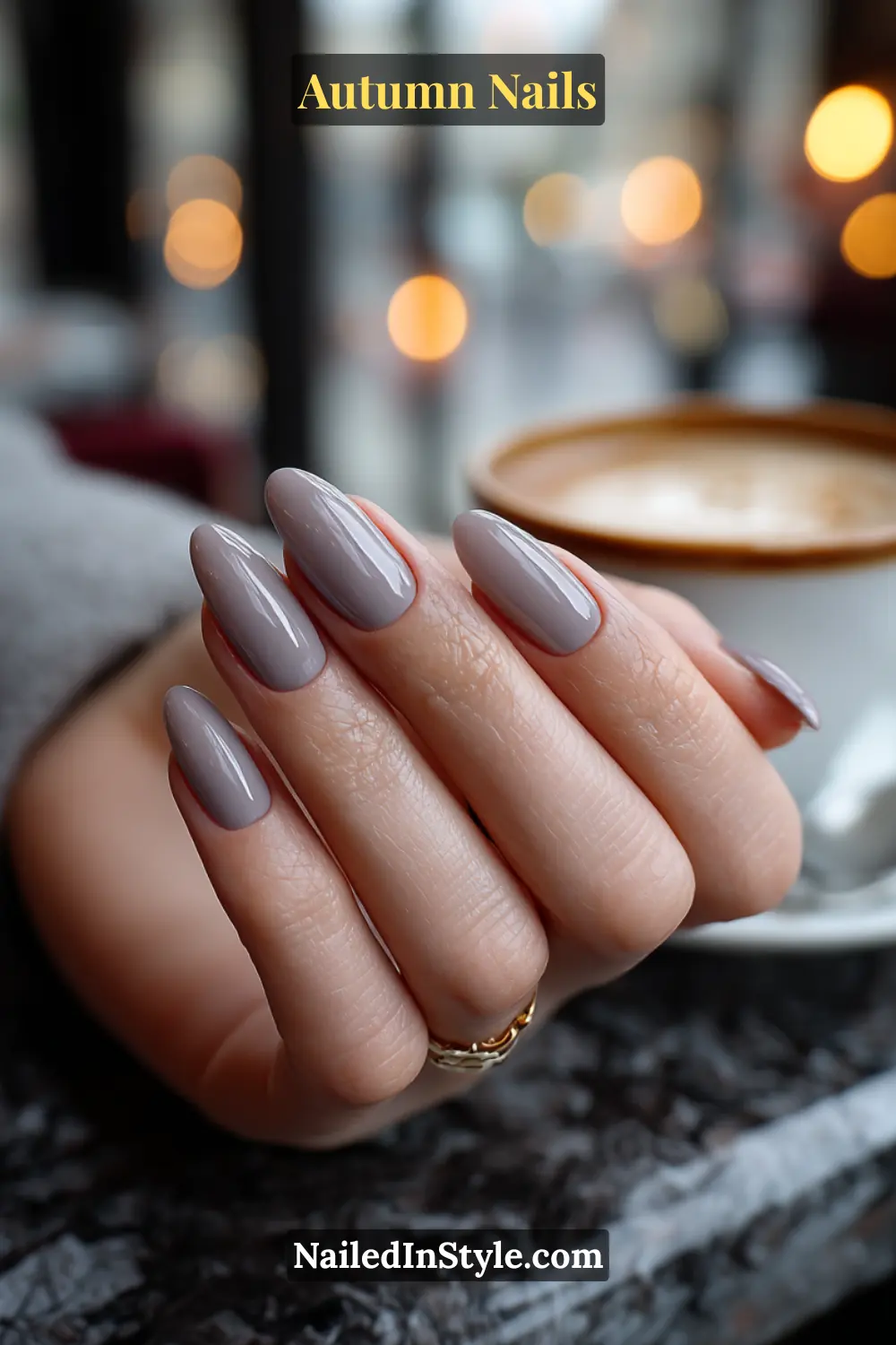 Close-up of smoky taupe aura autumn nails with taupe polish softly blurred into a grey halo, shown against a foggy café window.