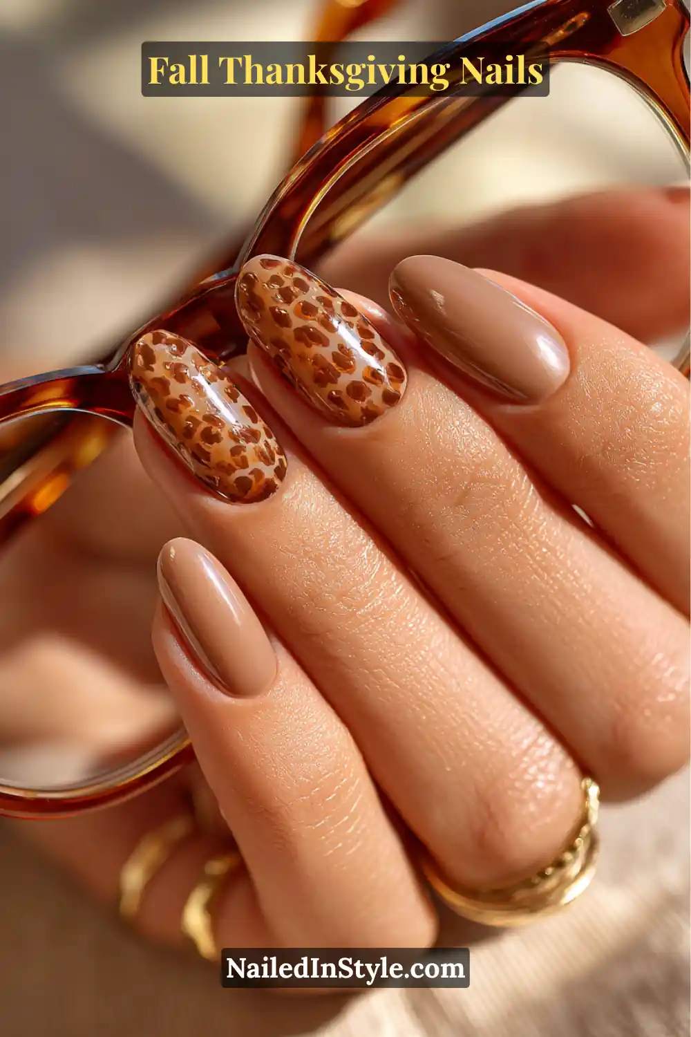 Close-up of Thanksgiving nails featuring two tortoiseshell accent nails paired with a mocha base, hand holding tortoiseshell glasses.