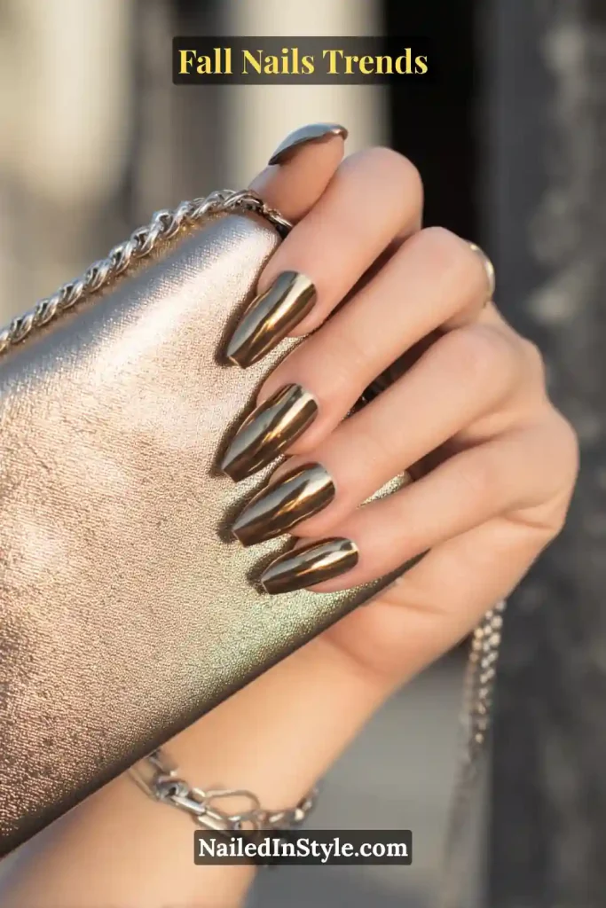 Fall bronze chrome square nails with a metallic mirror finish, styled while holding a street-style clutch for a bold autumn fashion statement.